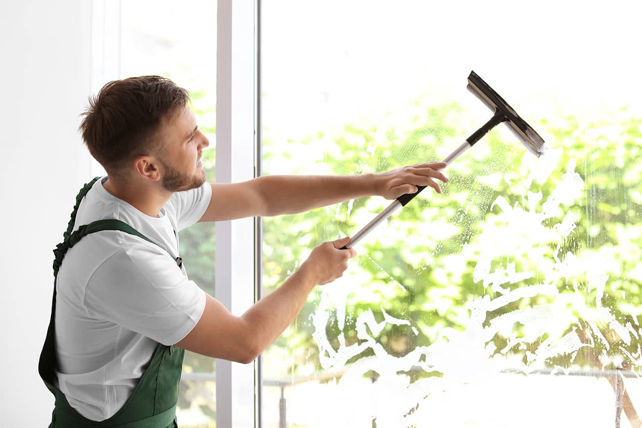 window cleaning professional using squeegee to clean interior window