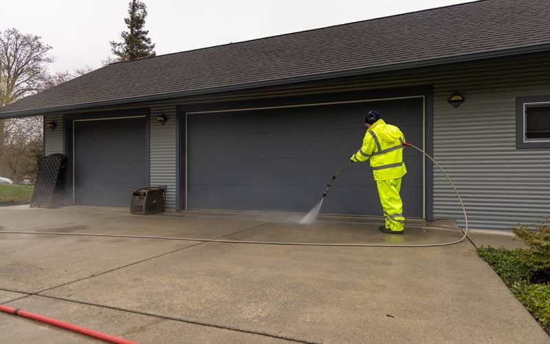 pressure washing professional pressure washing driveway in front of gray home