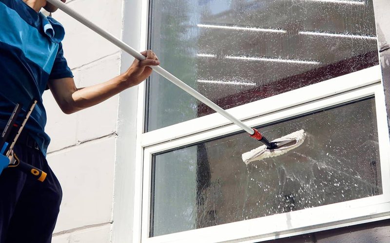window cleaning professional using extended soap brush to clean windows
